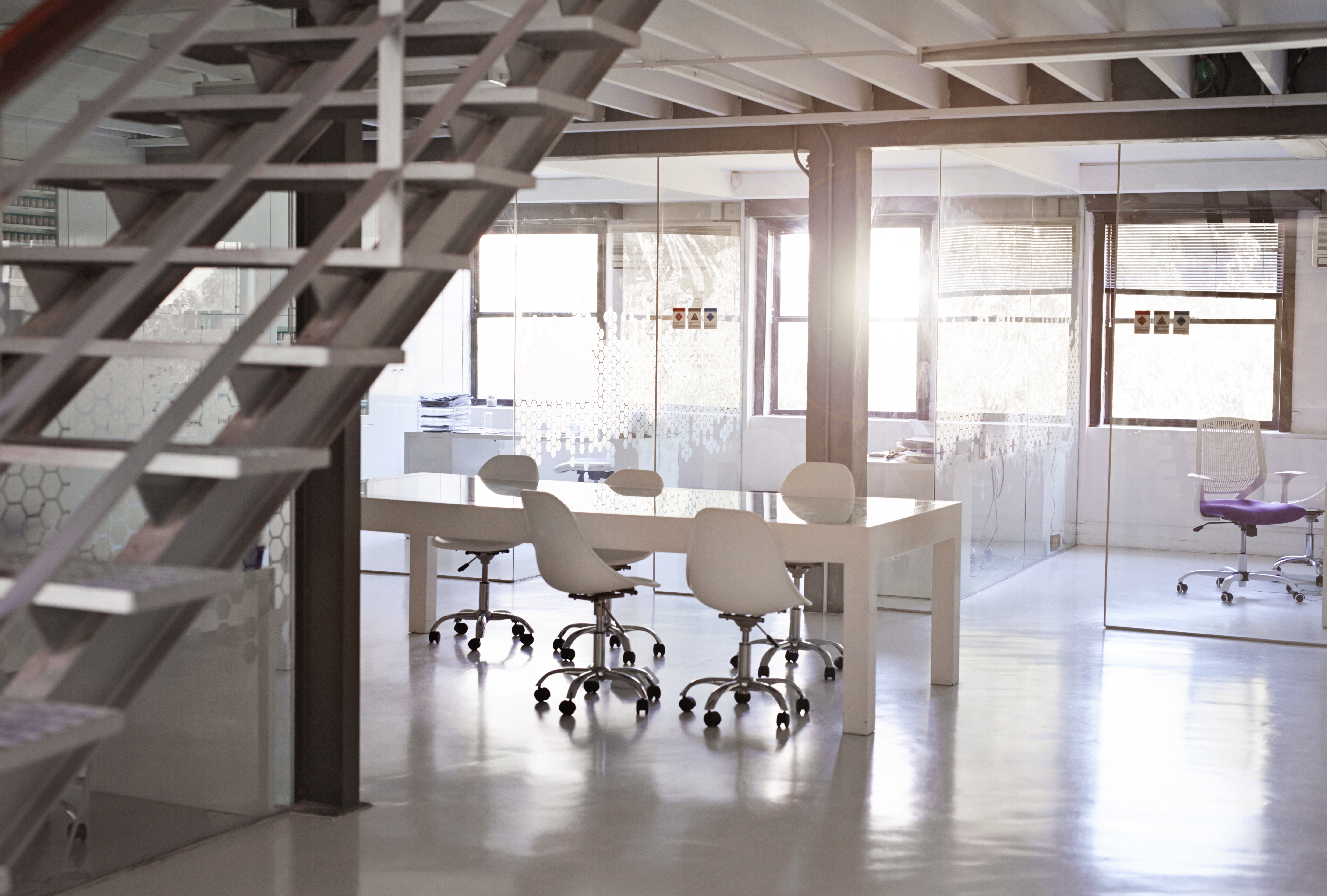 A bright, open office workspace seen past a stairwell
